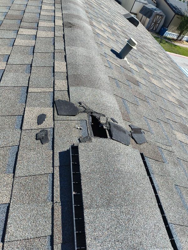 Shingles torn away beside a ridge vent