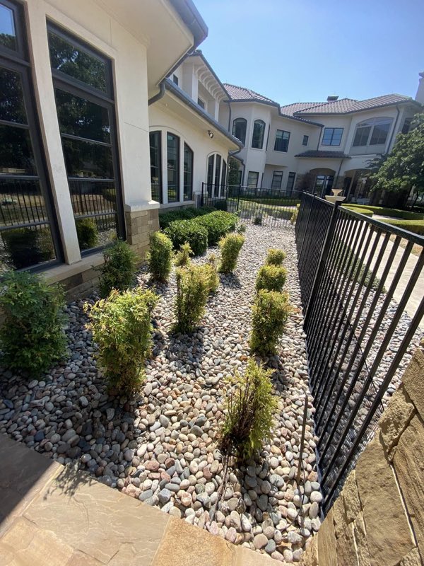 River rock bed and iron fence along the side yard