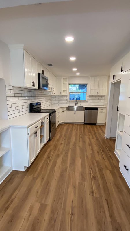 White shaker kitchen with subway backsplash and plank floor