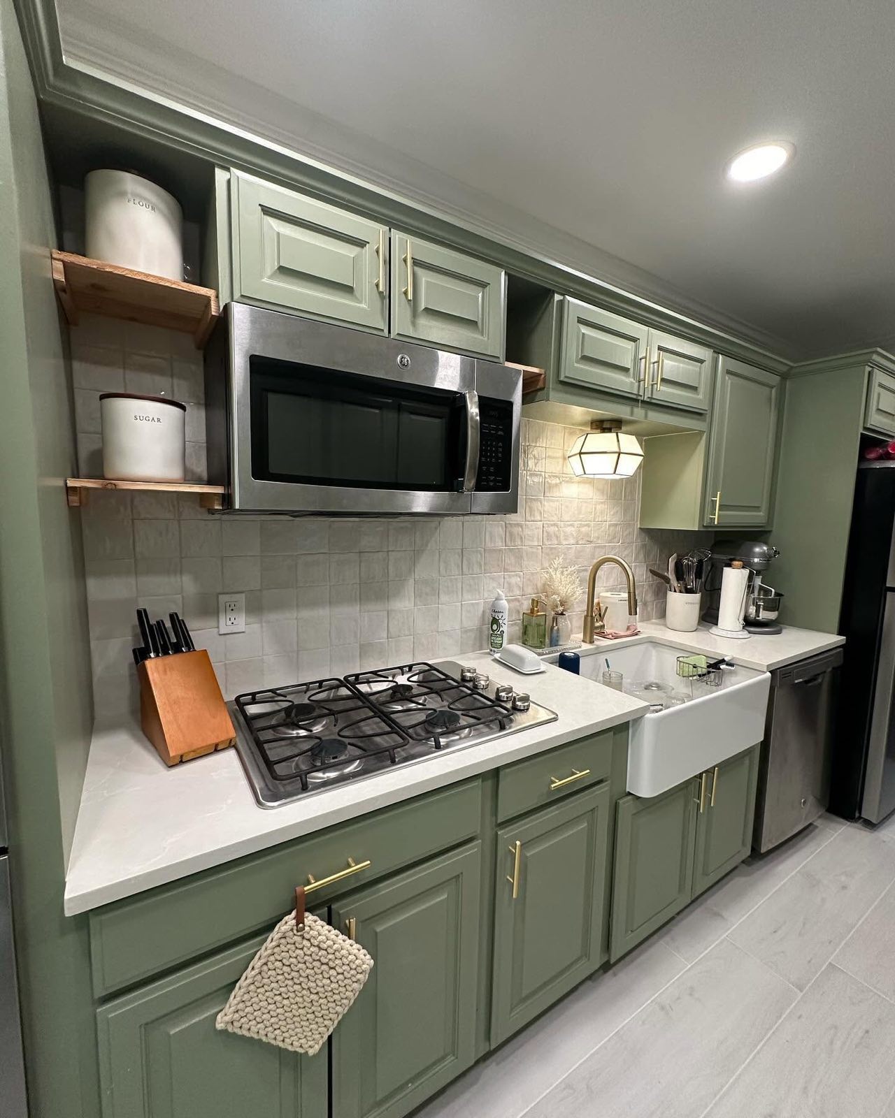 Green cabinet kitchen with farmhouse sink and open shelving