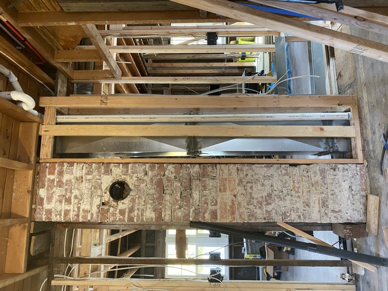 Framing taken back to studs around an exposed brick chimney